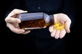 A close-up of the hands of a man holding a jar of fish oil capsules pours capsules on his palm Royalty Free Stock Photo
