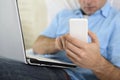 Close up hands of man lying on bed couch using mobile phone and computer working from home Royalty Free Stock Photo