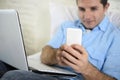 Close up hands of man lying on bed couch using mobile phone and computer working from home Royalty Free Stock Photo