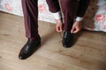 Close-up hands of a man tie laces on black shoes. A businessman in burgundy trousers and socks wears shoes before going Royalty Free Stock Photo