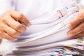 Close-up hands of a man in a white shirt searching for contract agreement documents in Stack of Group report papers clipped in