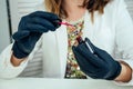 Close-up hands of manicurist professional master of manicure woman in a white jacket and black rubber gloves is apply a