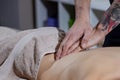Close up of hands of massage therapist doing back massage on back of young man Royalty Free Stock Photo