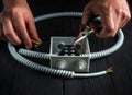 Close-up of hands of master electrician during work. Installing a cable or wire to gray junction box. Electrical connection in the Royalty Free Stock Photo