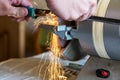 Close-up: the hands of a master sharpen a knife on a sharpening machine. Selective focus. Lots of bright glowing sparks