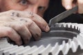 Close-up of hands of a mechanic repairing a cog wheel with a rasp