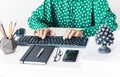 Close-up of hands middle-aged woman in green blouse typing on keyboard laptop computer, concrete holder with pencils and pens, Royalty Free Stock Photo