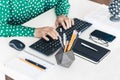 Close-up of hands middle-aged woman in green blouse typing on keyboard laptop computer, concrete holder with pencils and pens, Royalty Free Stock Photo