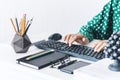 Close-up of hands middle-aged woman in green blouse typing on keyboard laptop computer, concrete holder with pencils and pens, Royalty Free Stock Photo