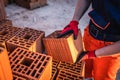 Close up on hands and midsection of unknown man construction worker taking clay brick blocks ar warehouse or construction site in Royalty Free Stock Photo