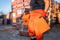 Close up on hands and midsection of unknown man construction worker taking orange hollow clay blocks ar warehouse or construction Royalty Free Stock Photo