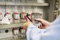 Close-up of hands with multimeter in electrical control panel. Engineer tests electrical automation box Royalty Free Stock Photo