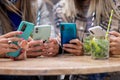 Close up of hands of multiracial group of four women using smartphones at the table in a cafe in the city with cocktails Royalty Free Stock Photo