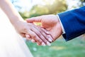 Close up hands of newlywed couple standing outside on a sunny day. Groom holding his brides hand with wedding band Royalty Free Stock Photo
