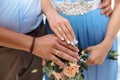 Close-up of the hands of the newlyweds with wedding rings, gently touch the wedding bouquet of peonies. Royalty Free Stock Photo