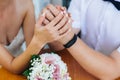 Close-up of the hands of the newlyweds with wedding rings, gently touch the wedding bouquet of peonies. Royalty Free Stock Photo