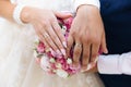 Close-up of the hands of the newlyweds with wedding rings, gently touch the wedding bouquet of peonies. Royalty Free Stock Photo