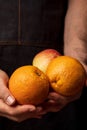 Close-up of hands offering fresh and raw fruits oranges, tangerines and rred kidney. Dark background. Royalty Free Stock Photo