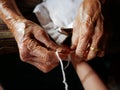 Hands of old woman tying a white string  Sai Sin  around her granddaughter hands - Thai traditional blessing from an elder one Royalty Free Stock Photo