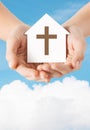 Close up of hands and paper house with cross Royalty Free Stock Photo