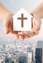 Close up of hands and paper house with cross Royalty Free Stock Photo