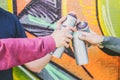 Close up hands of people holding color spray cans against the graffiti wall - Graffiti artists at work Royalty Free Stock Photo