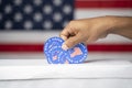 Close up of hands putting multiple I voted my Mail stickers inside the box with US flag as background - Concept of Vote by mail