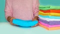 Close-up of hands putting stack of fresh bath towels. multi-colored rolls of towels in a wicker basket on a blue Royalty Free Stock Photo