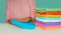 Close-up of hands putting stack of fresh bath towels. multi-colored rolls of towels in a wicker basket on a blue Royalty Free Stock Photo