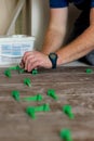 Close up hands of repairman laying tiles with tile leveling system on the floor in a new house