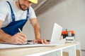 Close up of hands of repairman writing down details of an order on the clipboard while standing indoors during