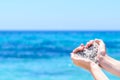 Close-up hands with sand in shape of heart against tropical turquoise sea