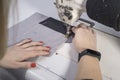 Close-up of the hands of a seamstress sewing clothes, sews fabric behind a sewing machine Royalty Free Stock Photo