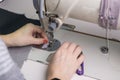 Close-up of the hands of a seamstress sewing clothes, sews fabric behind a sewing machine Royalty Free Stock Photo