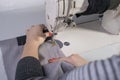 Close-up of the hands of a seamstress sewing clothes, sews fabric behind a sewing machine Royalty Free Stock Photo