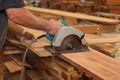 Close up hands of senior carpenter cutting a piece of wood against electric circular saw in carpentry woodshop. Woodworking concep Royalty Free Stock Photo