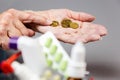 Close up of hands of senior woman counting a coinson near full of medicines little shopping cart. Gray background