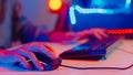 Close-up hands shot asia girl gamer use keyboard and mouse controller play video game with neon light computer in desk at home.