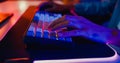 Close-up hands shot asia guy gamer use keyboard and mouse controller play video game with neon light computer in desk at home.