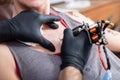 Close-up of the hands of a skilled artist making the contour of a tattoo