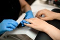 Close-up of hands of skilled manicurist filing female nails with nail file