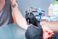 Close-up of the hands of a skilled tattoo artist wearing black gloves