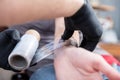 Close-up of the hands of a skilled tattoo artist wrapping a tattooed client