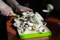 Close-up of hands with sliced fresh mushrooms on a cutting board. Homemade vegetarian cuisine. Sunlight from window, shadows on Royalty Free Stock Photo