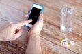 Close up of hands with smartphone, pills and water