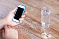 Close up of hands with smartphone, pills and water Royalty Free Stock Photo