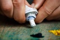 Close up of hands squeezing white oil paint on palette. Royalty Free Stock Photo