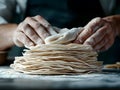 Hands stacking thin dough sheets covered with flour in a kitchen setting Royalty Free Stock Photo