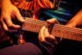 close-up of hands strumming an electric guitar with plectrum