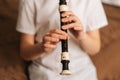 Close-up hands of talented adorable little girl playing flute sitting on bed in bedroom. Royalty Free Stock Photo